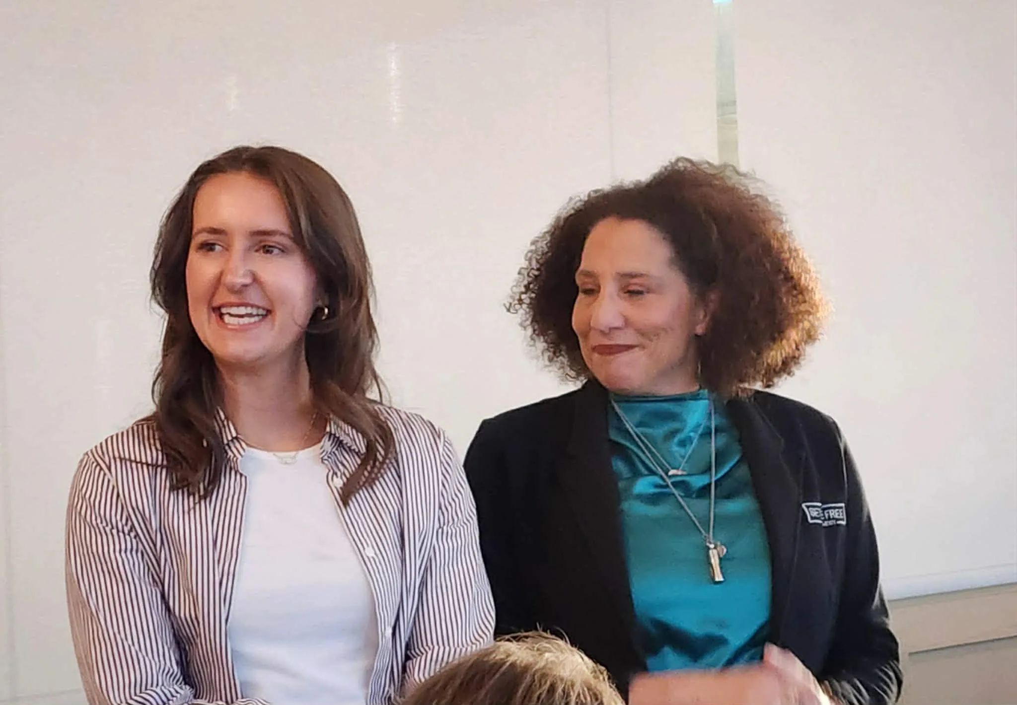 Two women smiling at an indoor event