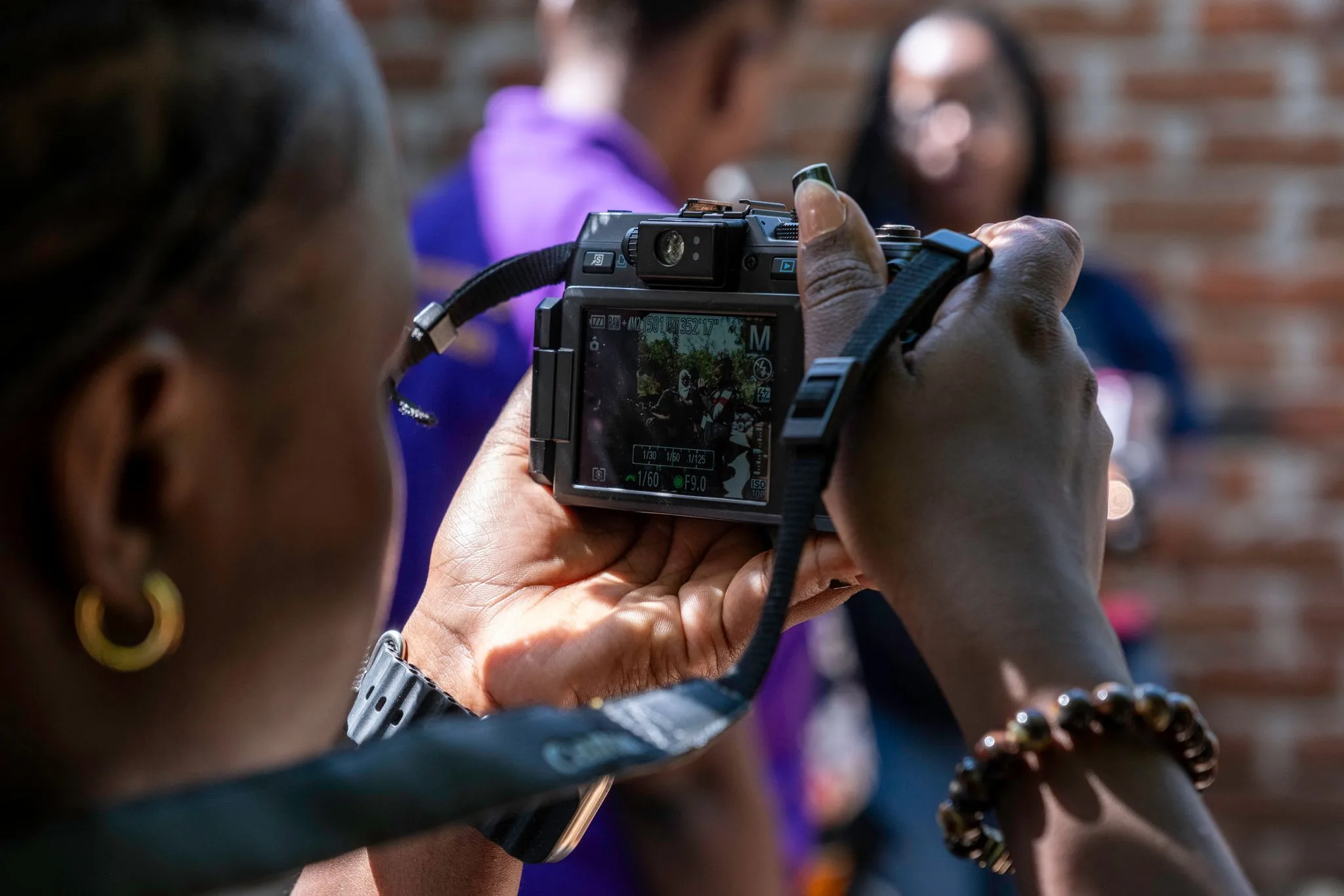 Hands holding a compact camera, its screen showing a group of people