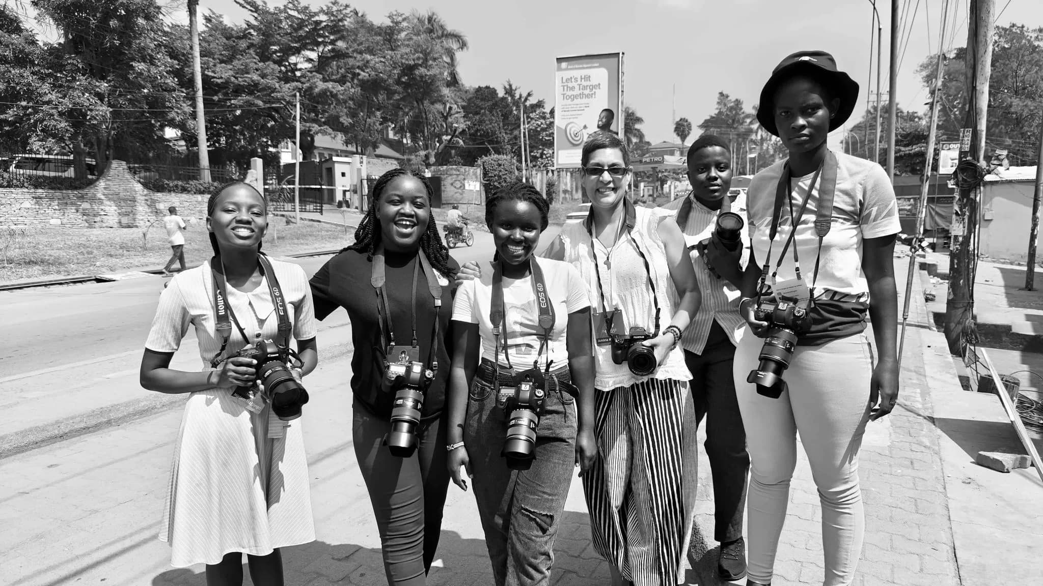 Black and white photograph of six women walking down a street carrying cameras