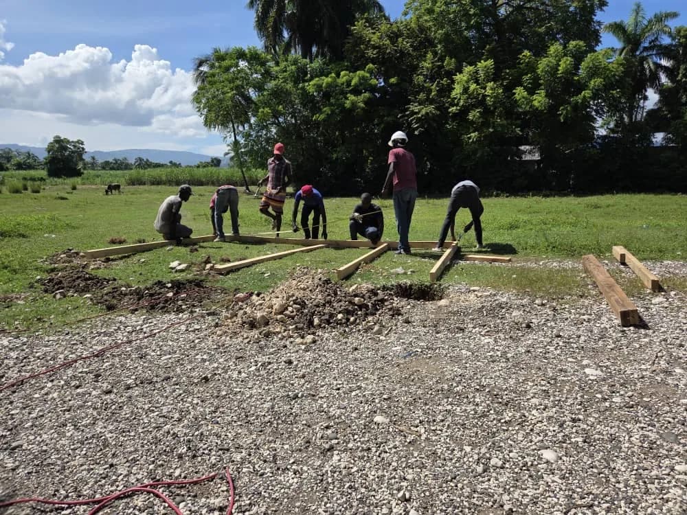 Workers setting wooden posts in a grassy field
