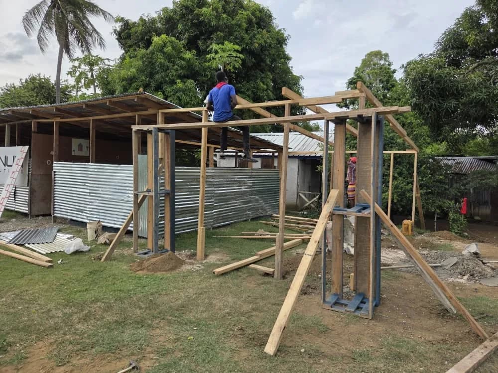 A wooden frame going up beside a school building, a worker standing on top