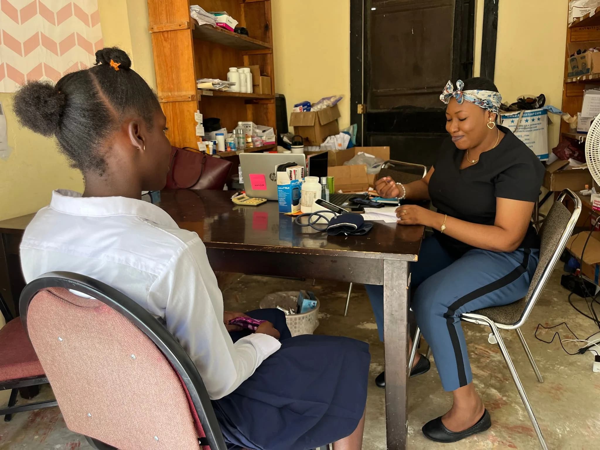 A nurse at a desk with medical supplies talking with a student