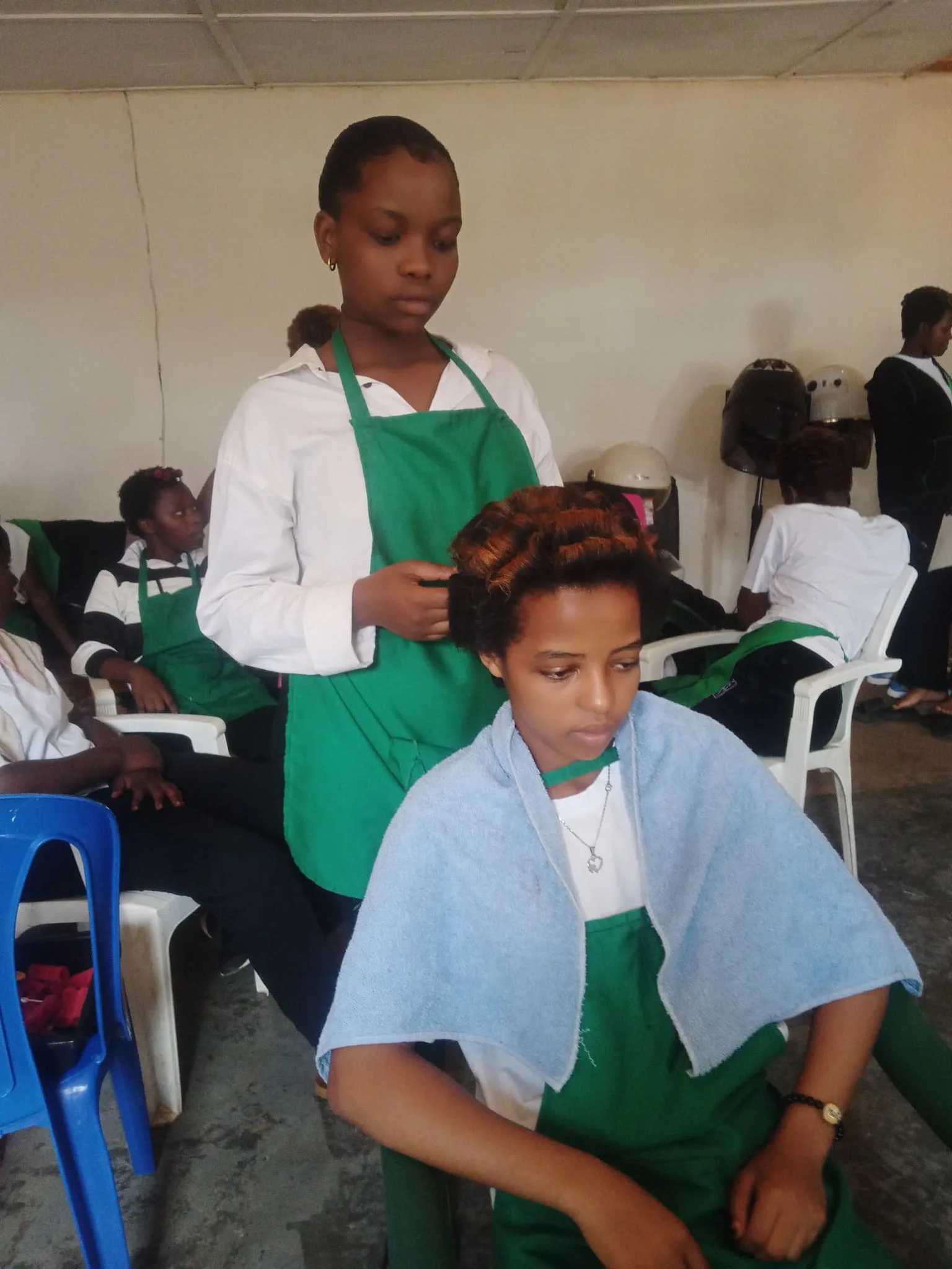 A hairdressing student styling another student’s hair in a classroom